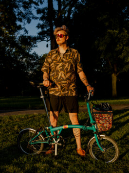 Man standing with a turquoise Brompton bike in the evening sun 