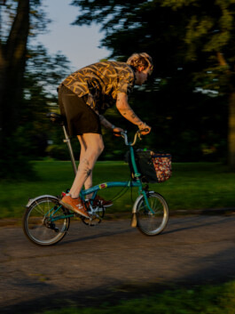 Cyclist riding a turquoise Brompton on an urban street 