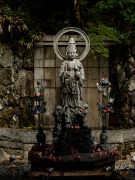 Stone statue of Buddhist figure in forested area, Japan 